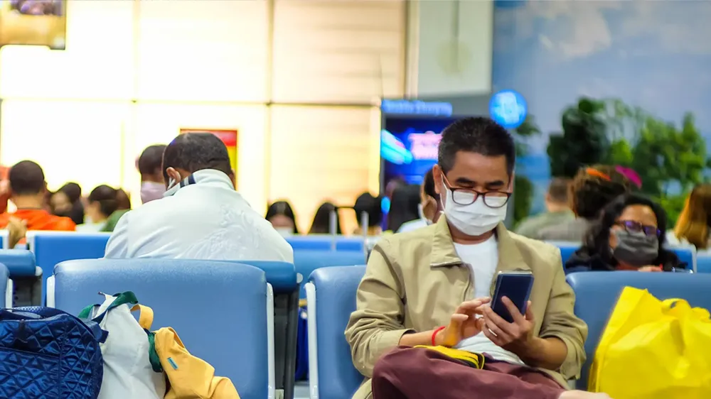 man wearing mask to protect against covid-19 coronavirus sits in airport gate